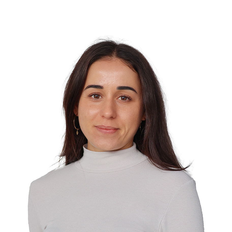 Eine junge Frau mit dunklen, schulterlangen, kurzen Haaren und einem weißen Oberteil.