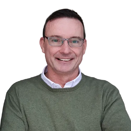 Ein lächelnder Mann mit grauen, kurzen Haaren und einem hellgrünen Oberteil.